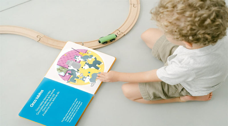Bilingual child uses play time to sing along to one of Binibi's children's musical books, Sol Solecito & Other Nursery Rhymes, which features popular Spanish nursery rhymes.  