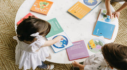 Bilingual children enjoying their bilingual books for kids as they play sound books togethr during their bilingual playdate.