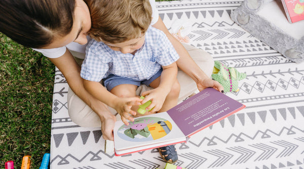 Bilingual mother and son browse through one of Binibi's interactive musical books for toddlers, Los Pollitos Dicen, that features catchy Spanish nursery rhymes.