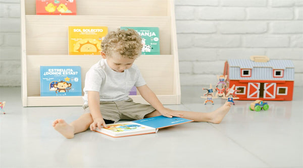 Bilingual toddler enjoying Binibi's bilingual children's books as he plays a sound book (featuring Binibi's collection of musical books and sound books)